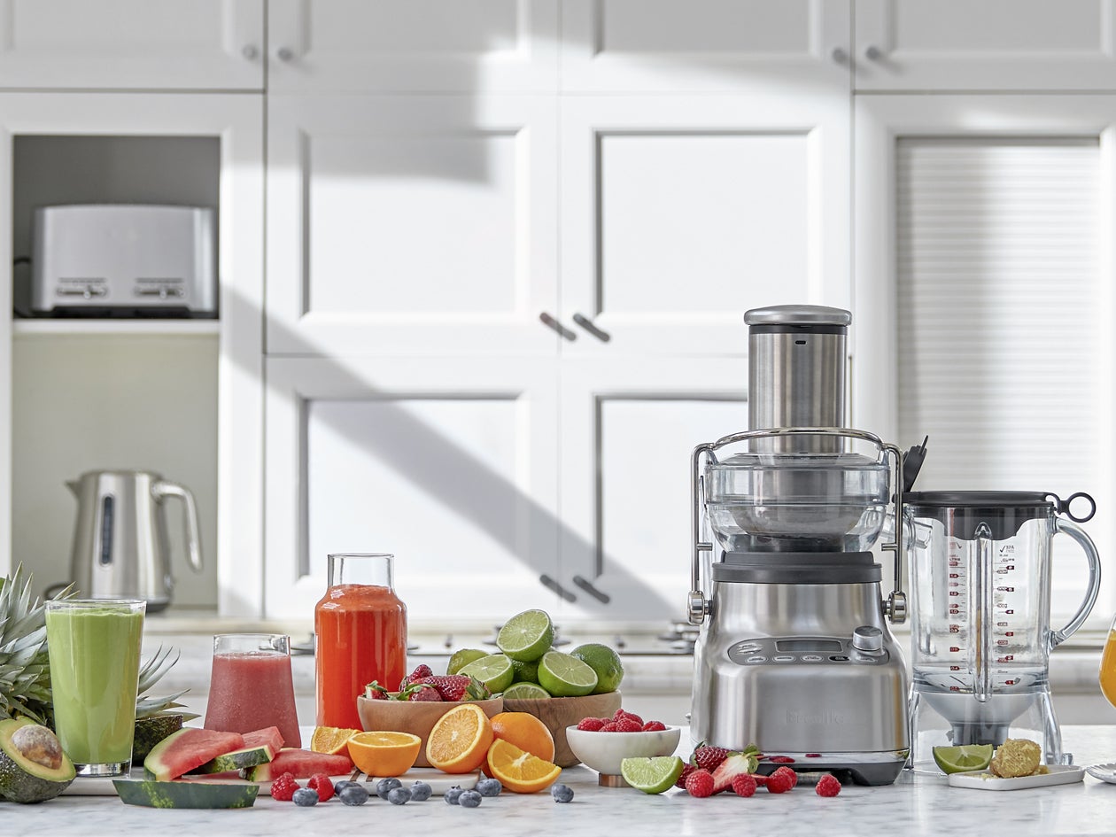 Appliance shown with fresh fruit, vegetables, and glasses of juice and smoothies.
