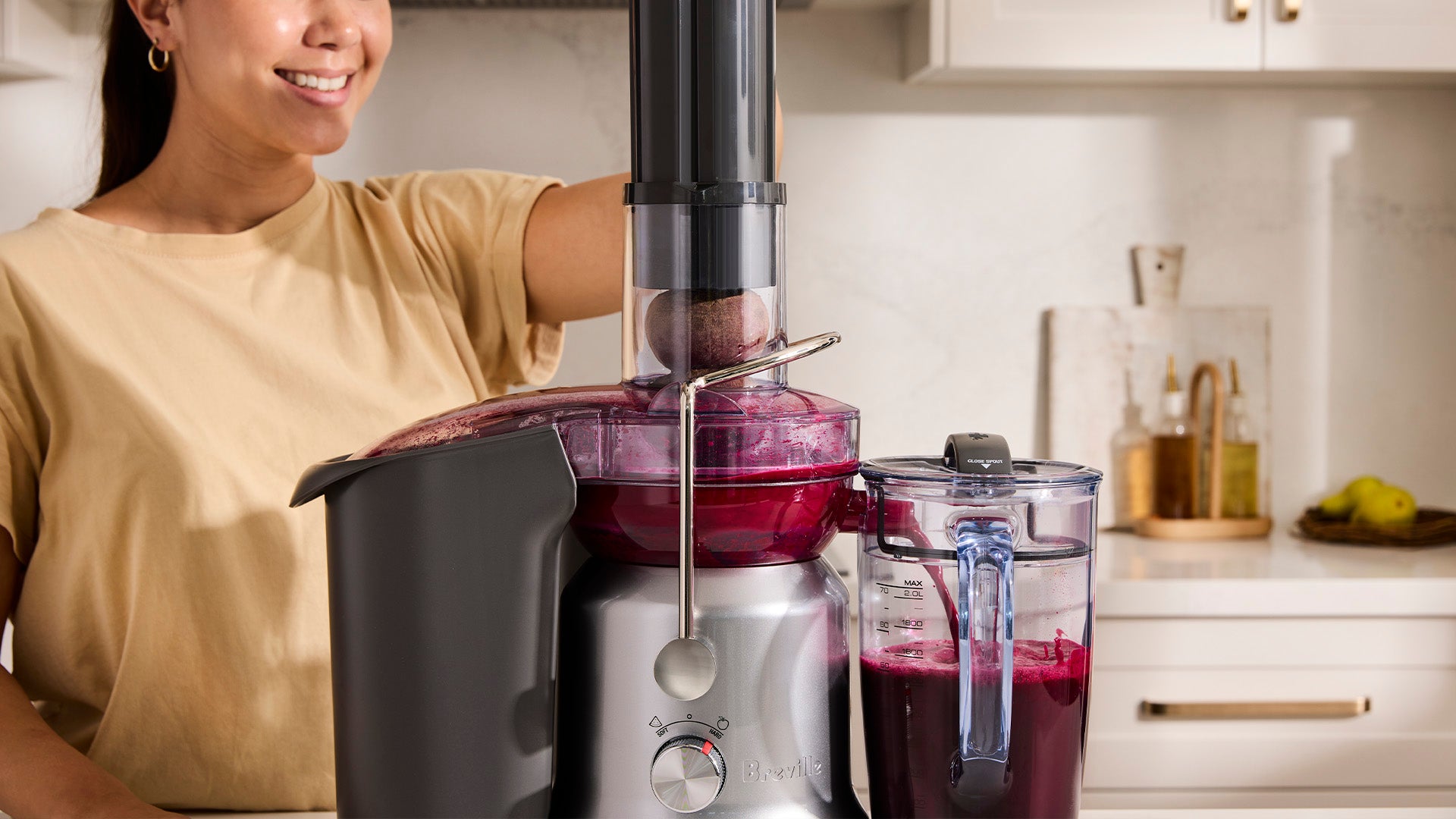 Person using a juicer to make fresh beetroot juice in a bright kitchen.