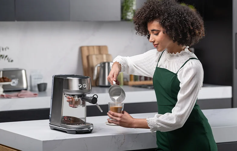 Barista pouring milk into latte