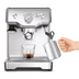 Front view of someone using the steam wand and a glass of coffee sitting on the Duo-Temp Pro.