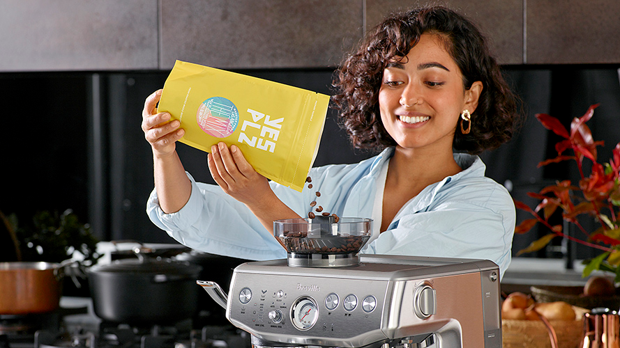woman putting coffee beans in espresso machine