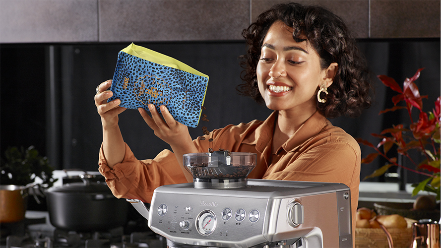 woman putting coffee beans in espresso machine