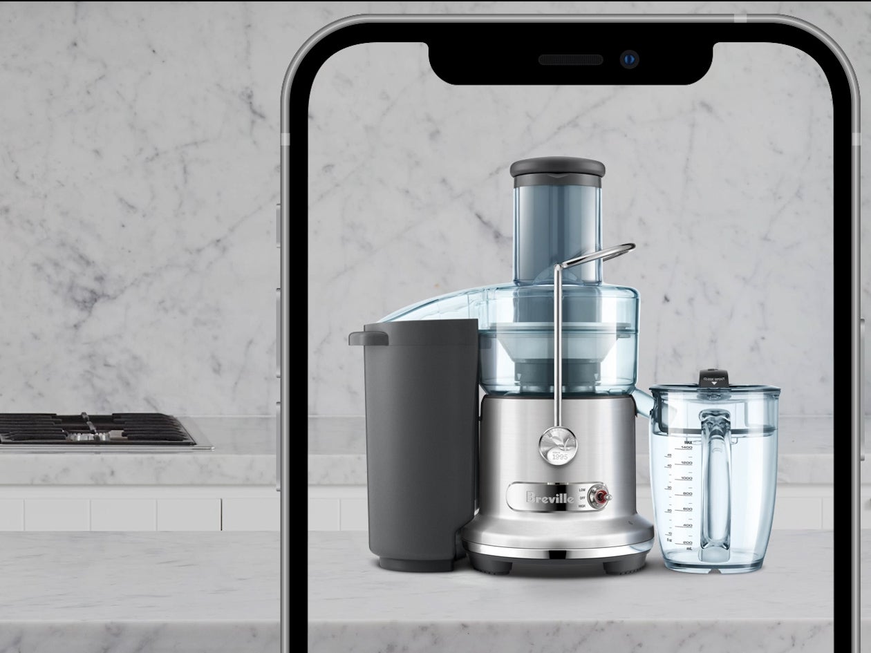 Juicer and juice jug displayed on a marble kitchen counter, framed within a large smartphone screen.